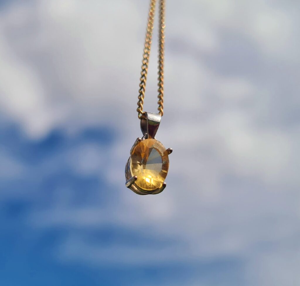 A Jemagic natural citrine pendant, with a cloudy sky background.