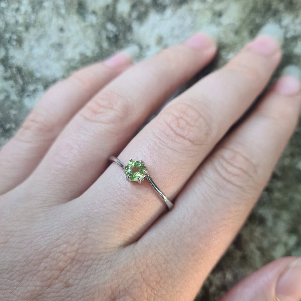 Jemagic peridot ring being worn with textured rock background
