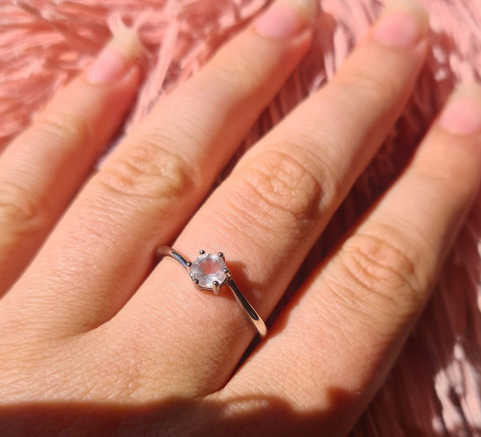 Rose quartz ring being worn with fluffy pink fabric background Jemagic rose quartz ring being worn with fluffy pink fabric background