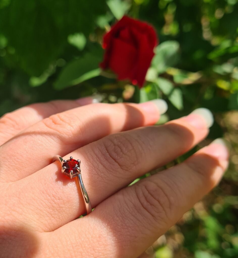Jemagic Garnet Ring being Worn with a Red Rose in the Background