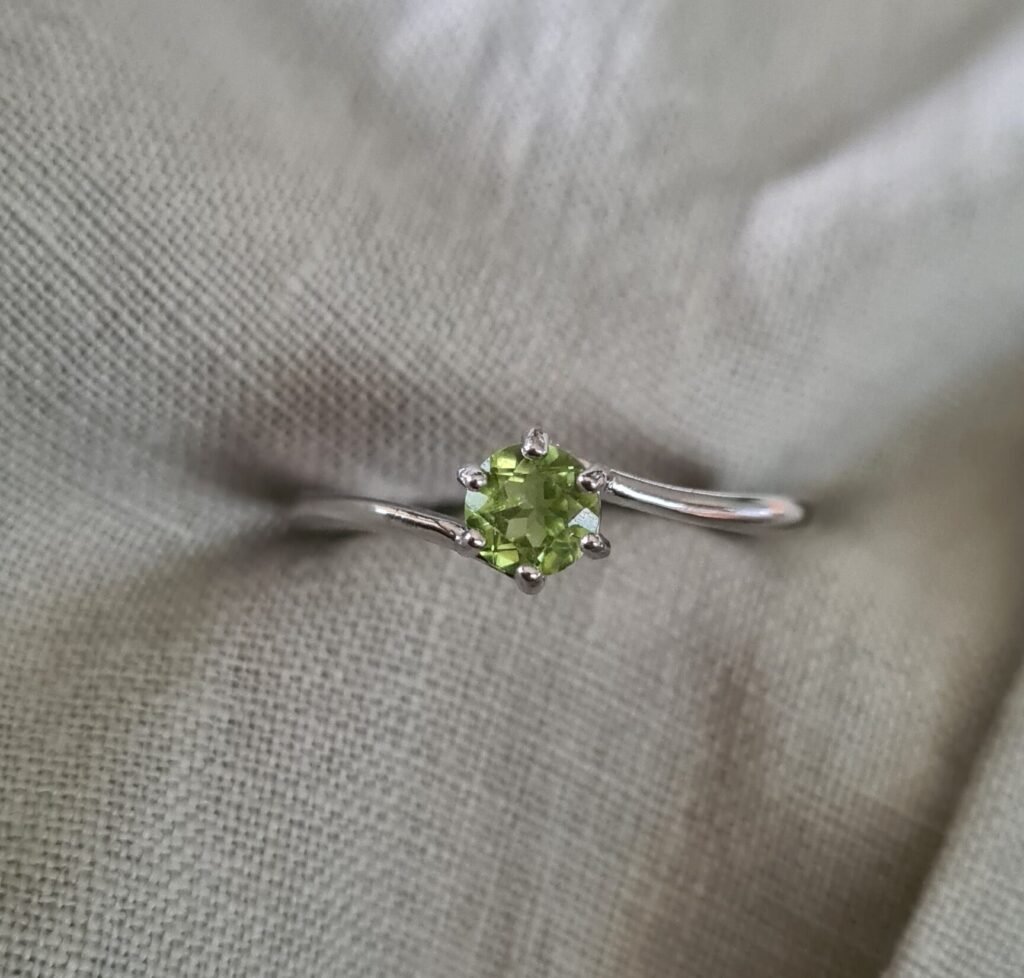 Jemagic peridot ring close up with green linen background