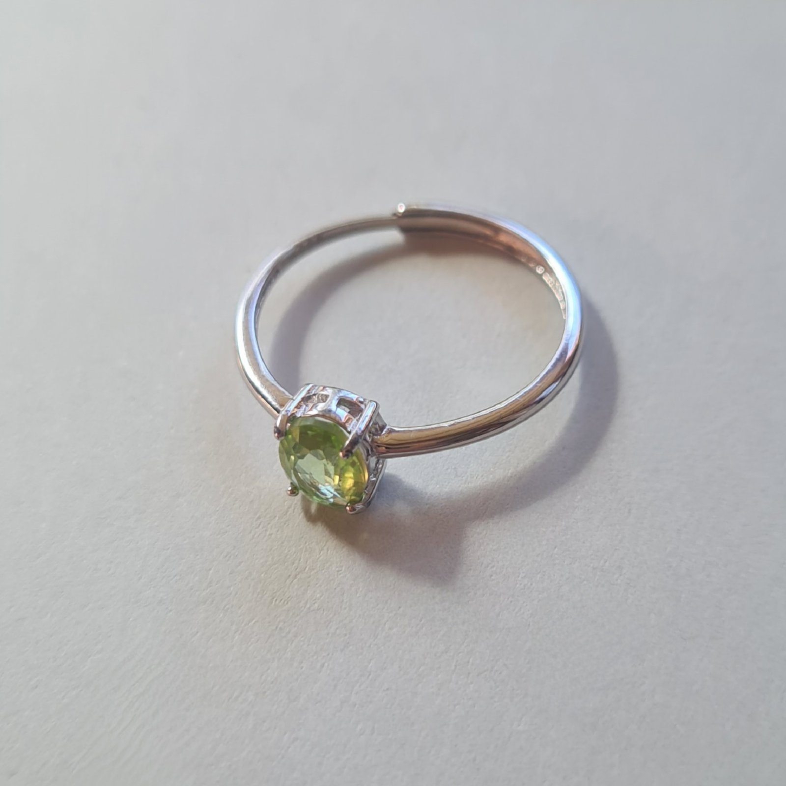 Oval cut Jemagic peridot ring on silver background - side view Oval cut Jemagic peridot ring on silver background - side view