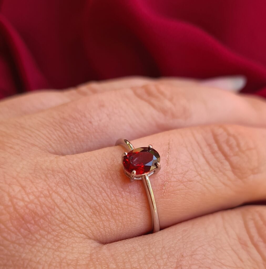 Jemagic Instagram post featuring an oval cut garnet ring with red fabric background